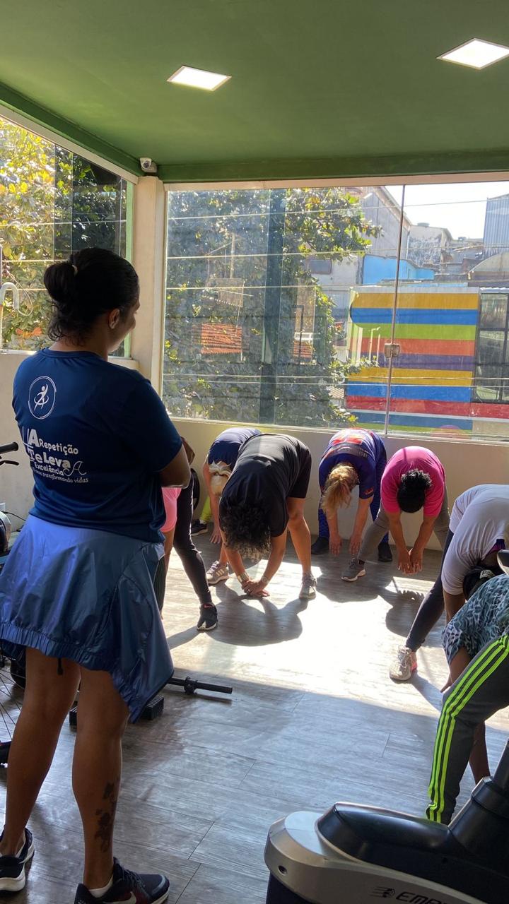 Turma alongando ao ar livre com a professora Fabiana orientando